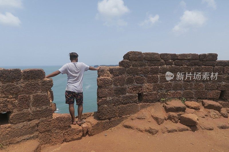 一名印度男子站在Cabo De Rama堡垒废墟上俯瞰大海，印度果阿